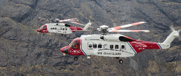 Two Mountain Rescue helicopters flying through the hills