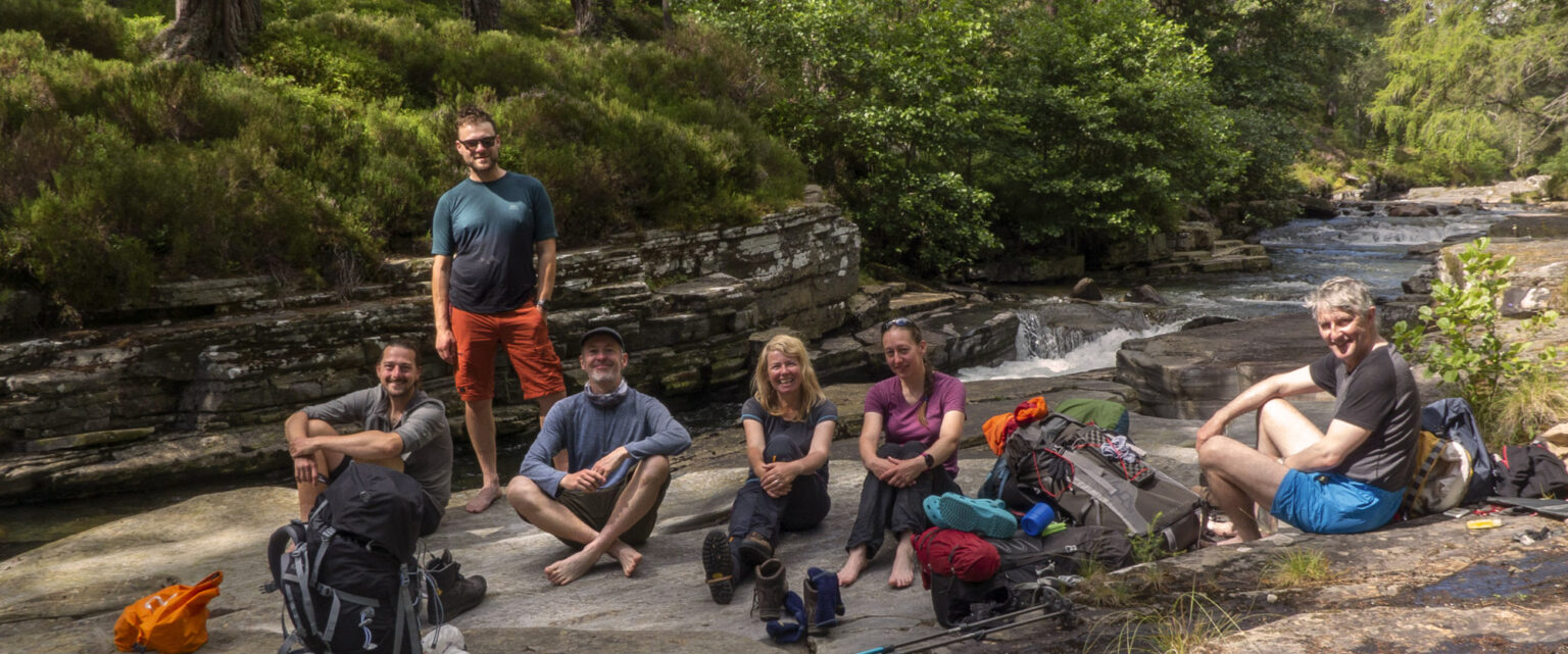 Group of people sitting on a rock by a river